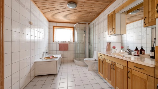 Romslig flislagt bad i hovedetasjen med stor innholdsrik og profilert baderomsinnredning med god skapplass. Frittstående badekar, dusjkabinett og toalett