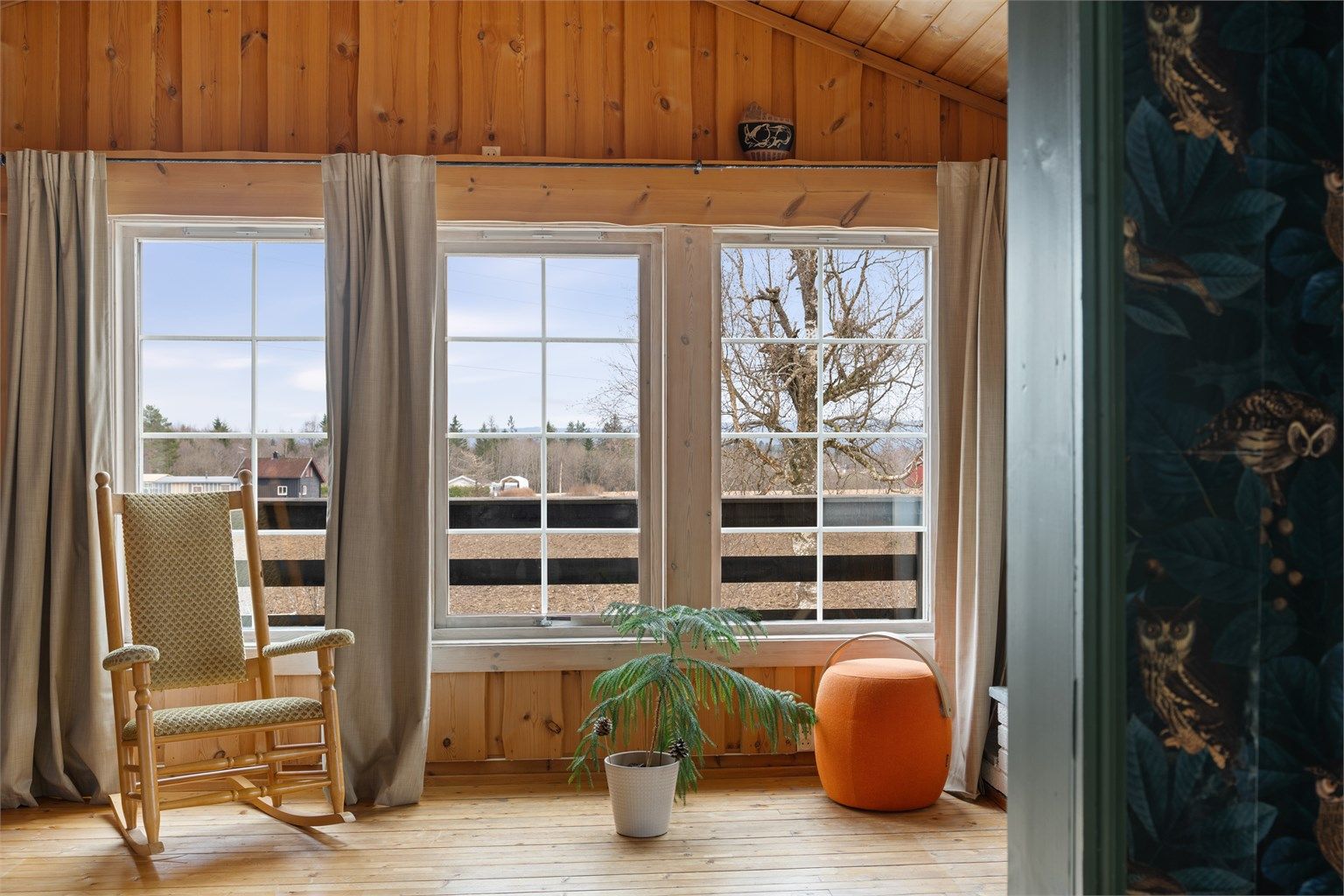 Store vindusflater i peisestuen slipper inn rikelig med dagslys og gir utsyn over eiendommen.