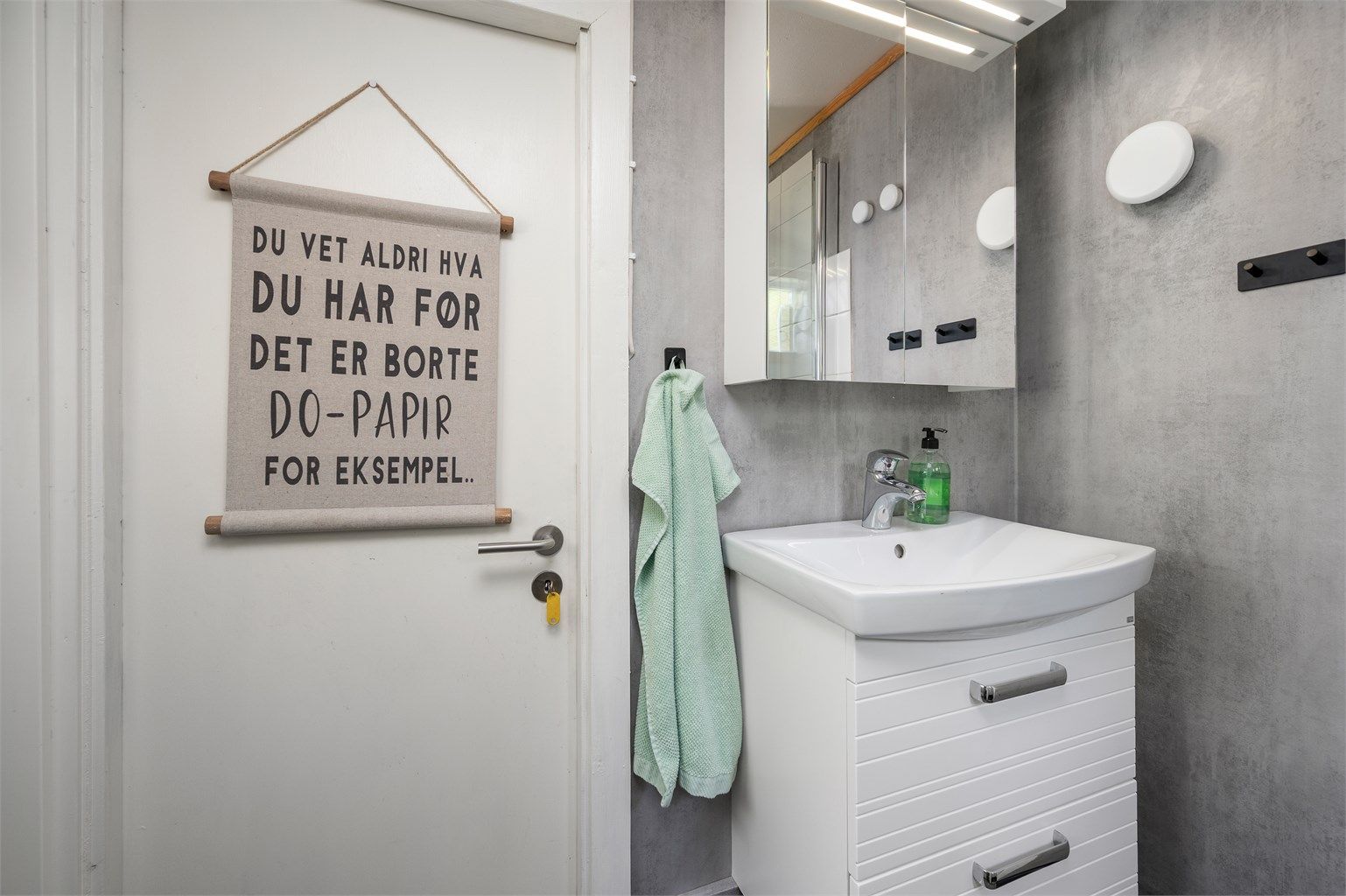 Badet har servantskap med overskap med speil og lys. 