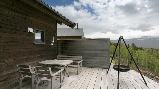 Skjermende levegg skaper en lun og privat uteplass for måltider under åpen himmel.