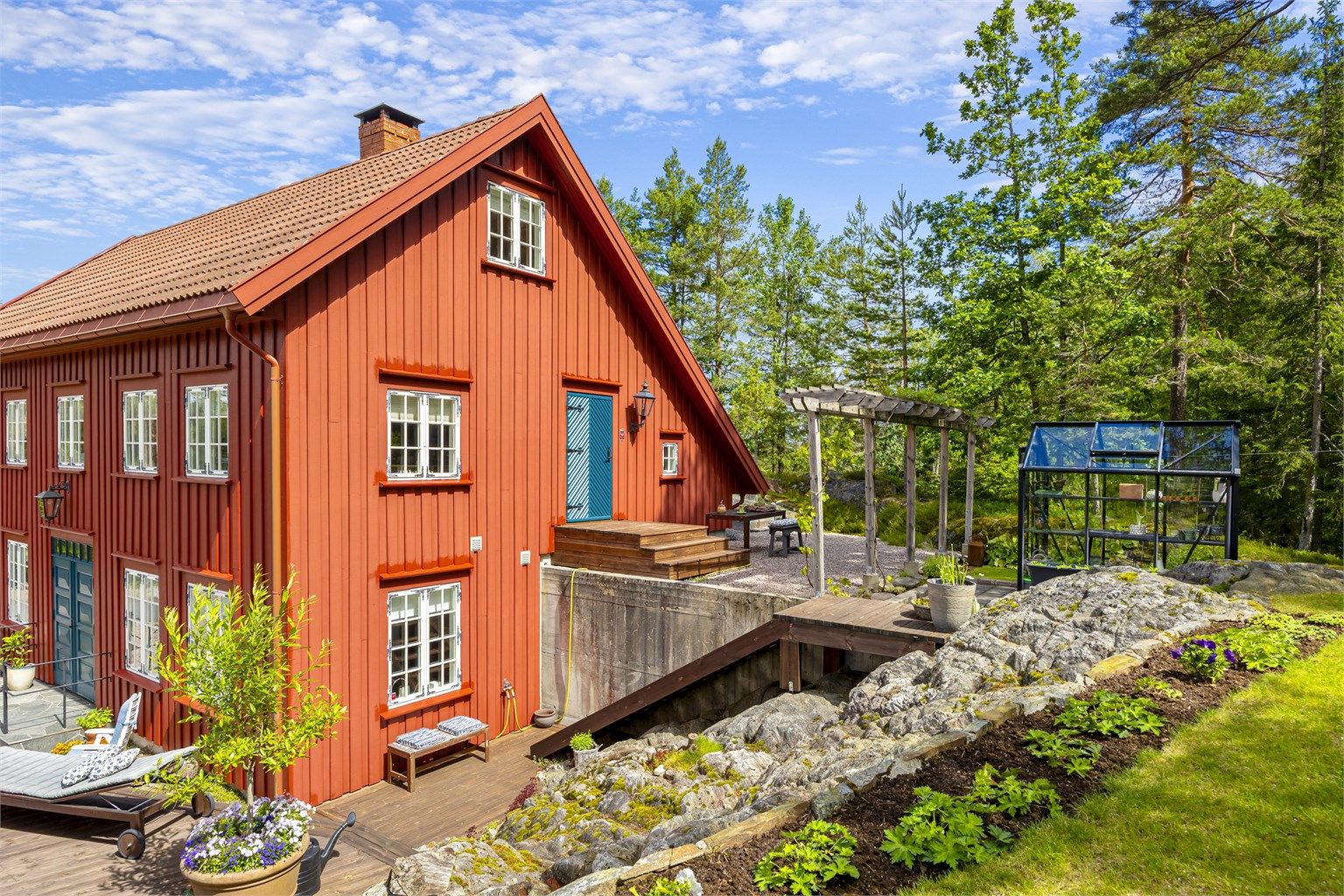 Boligen er bygget på en skrånende tomt med forstøtningsmurer i betong.