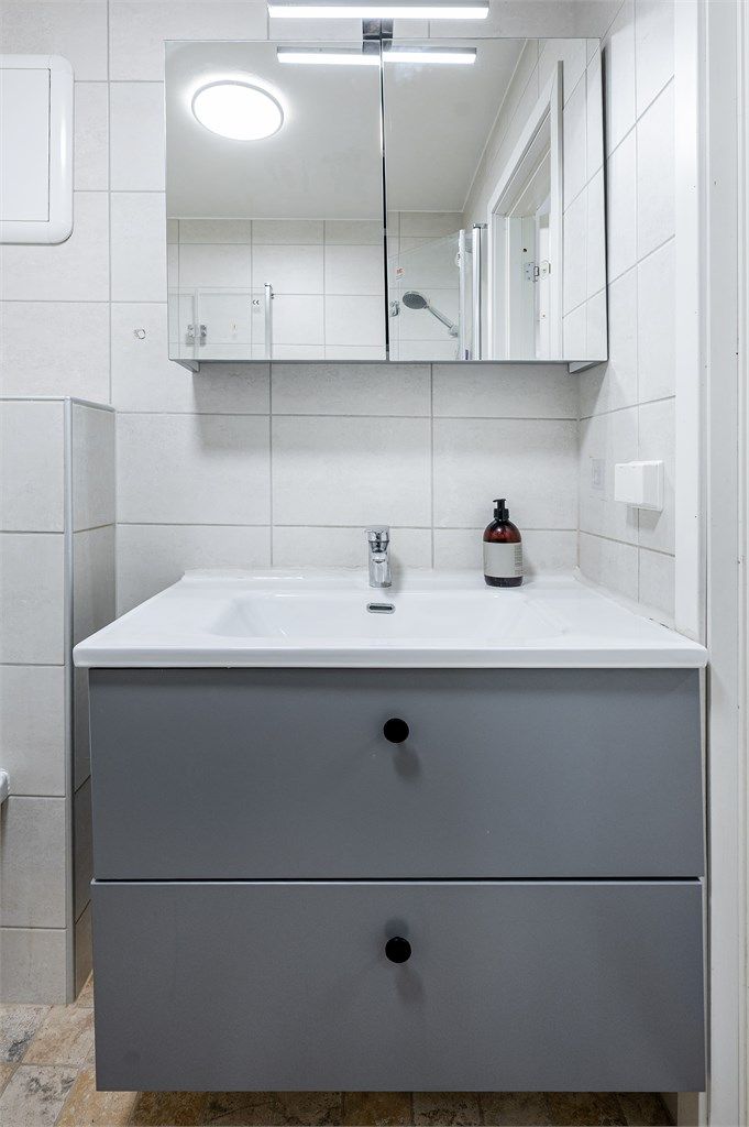 Badet er utstyrt med dusjhjørne, vegghengt toalett og en nyere servantinnredning.