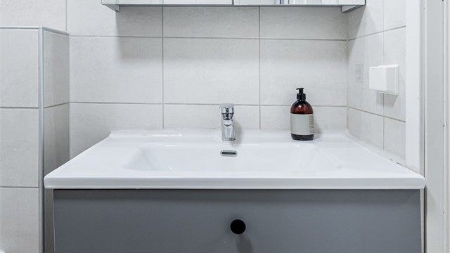 Badet er utstyrt med dusjhjørne, vegghengt toalett og en nyere servantinnredning.