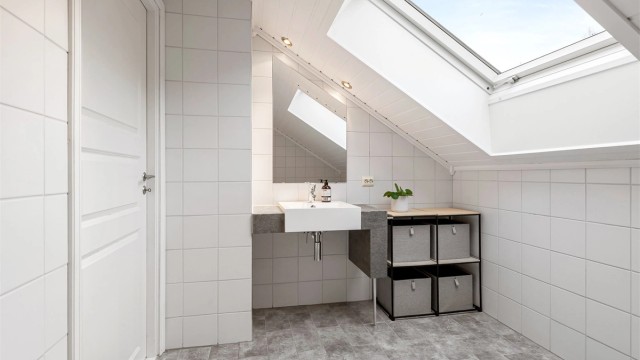Badet i loftsetasjen er helfliset og utstyrt med badekar.