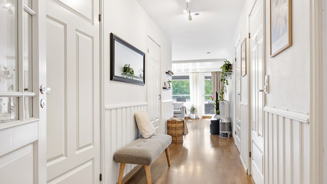 Gangen har profilerte dører, enkelte med glassfelt, som fører inn til leilighetens rom.
