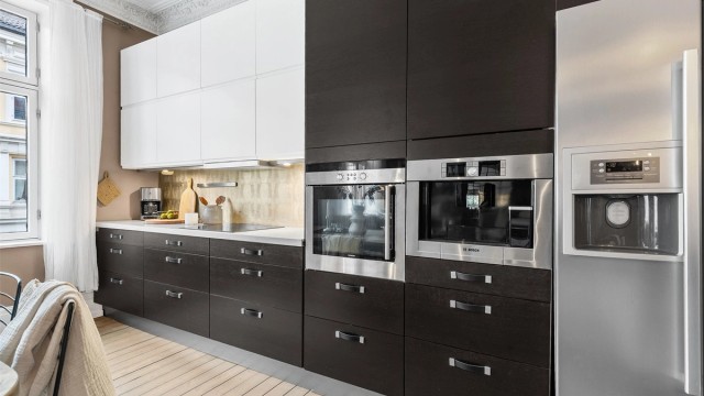 Åpen kjøkkenløsning. Innredningen er fra ukjent årstall med slette fronter. Benkeplate av stein. Nedfelt oppvaskkum med ett-greps kjøkkenarmatur.