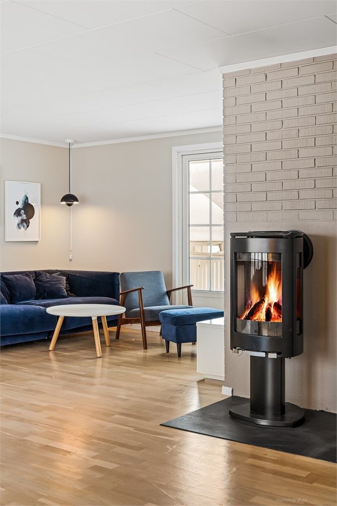 Frittstående Jøtul peisovn med plate på gulv og murvegg