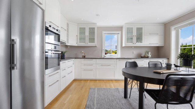 Lekkert og tidløst kjøkken med profilerte fronter og benkeplate med laminert overflate, samt rikelig med skap- og benkeplass.