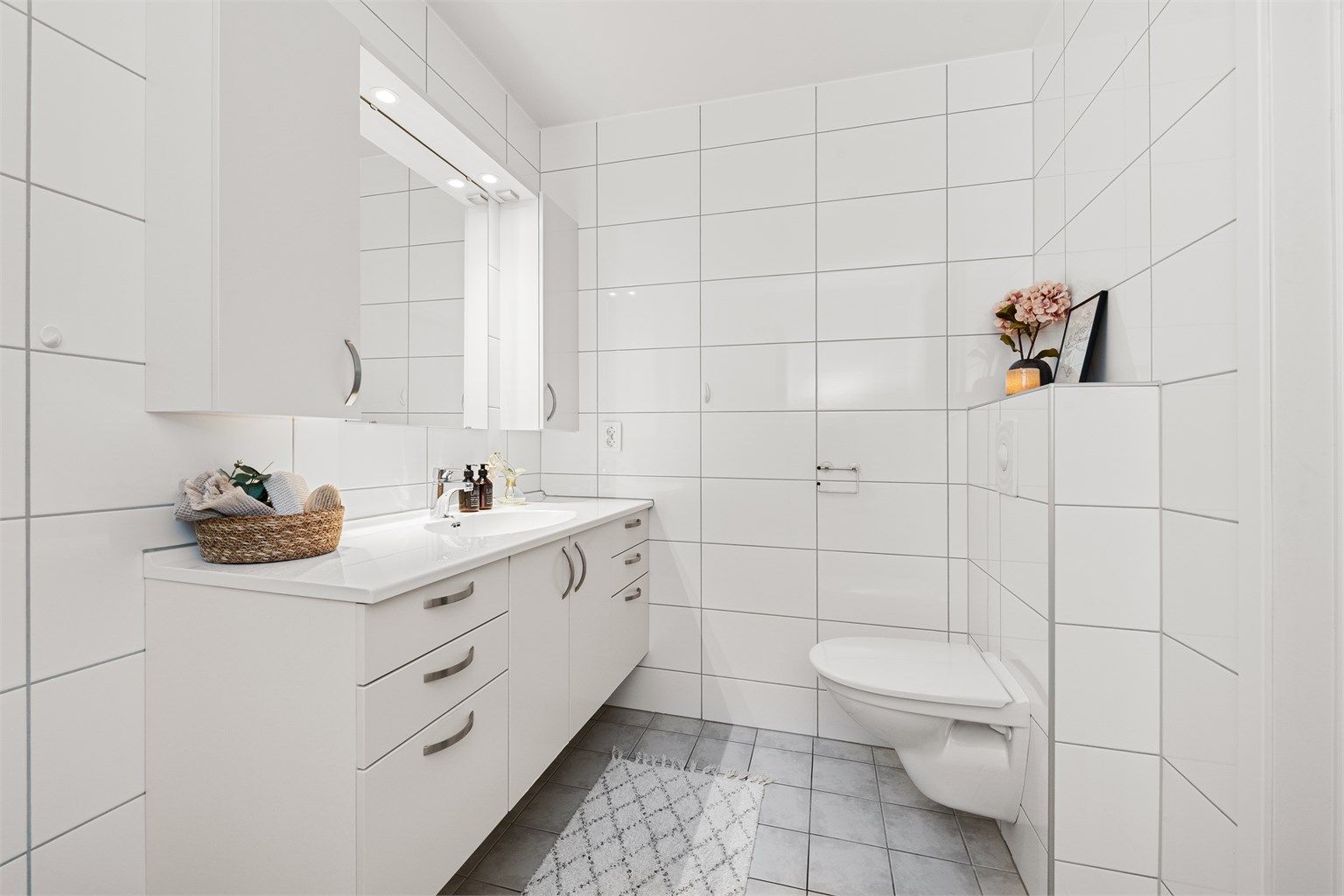 Badet har flislagte overflater, gulvvarme og innredning fra HTH.