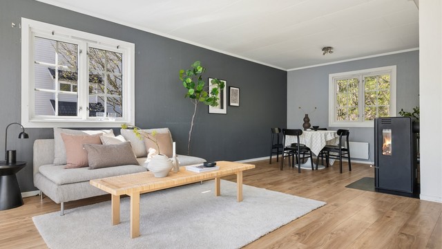 Rommet er lyst og luftig, med plass til både sofagruppe og spisebord.
