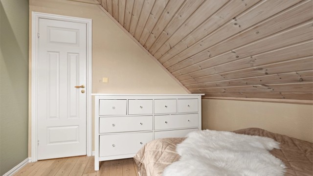Malt panel på veggene og god plass til kommoder under skråtaket.