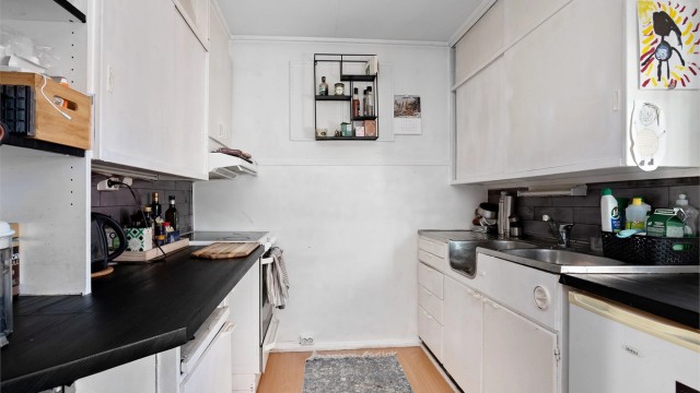 Kjøkkenet i utleiedelen har innredning med glatte fronter, benkeplater av tre og benkeplate av rustfritt stål med nedfelt oppvaskkum.