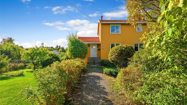 Innholdsrik og grønn tomt med velholdte busker og plenarealer rundt boligen.