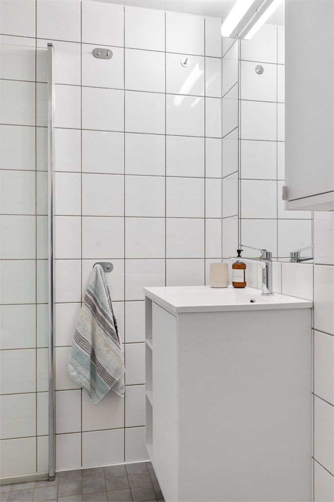 Badet har vegghengt servant med armatur og speil med overlys.