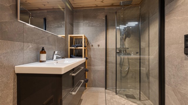 Badet har toalett, downlights og gulvvarme, servant med skuffer og et speil med integrert belysning. Dusjhjørne med innfelte glassdører.