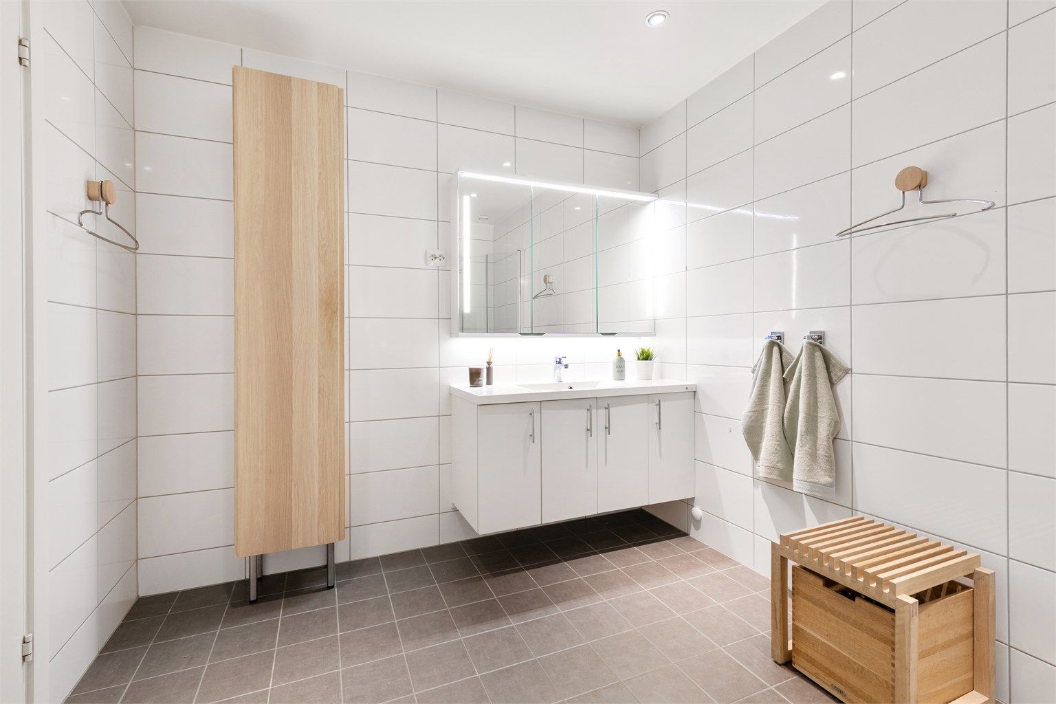 Hvit baderomsinnredning med dører samt frittstående skap gir gode oppbevaringsmuligheter