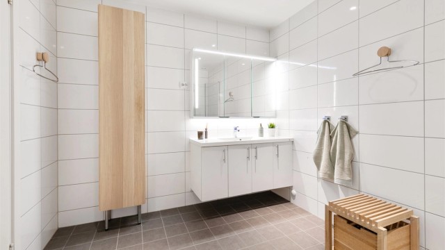 Hvit baderomsinnredning med dører samt frittstående skap gir gode oppbevaringsmuligheter