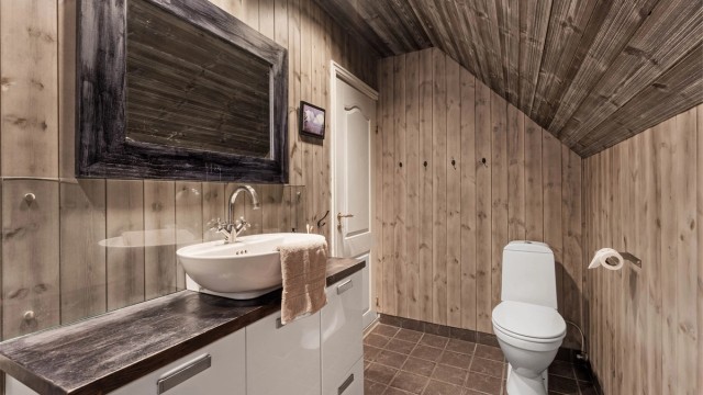 Badet er utstyrt med servantinnredning, toalett og dusjkabinett.