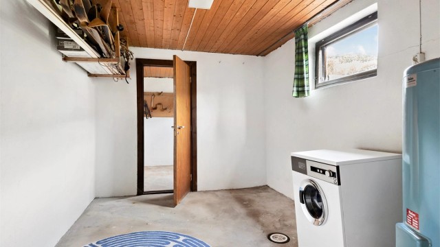 Praktisk vaskerom i kjeller med betonggulv og opplegg for vaskemaskin.