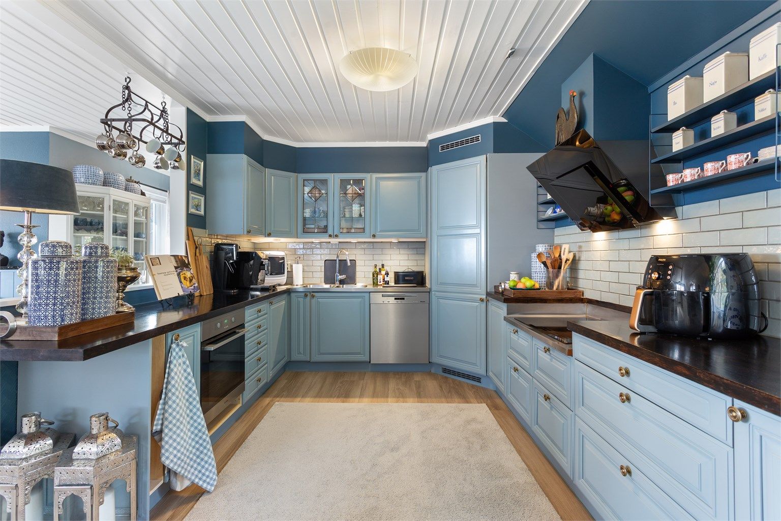 Kjøkkeninnredning fra byggeåret med profilerte fronter, benkeplate i tre og integrerte hvitevarer.