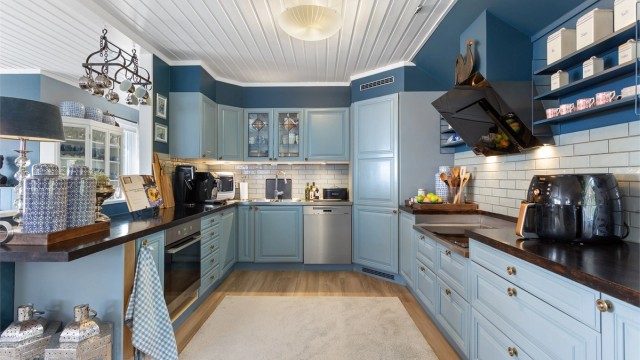 Kjøkkeninnredning fra byggeåret med profilerte fronter, benkeplate i tre og integrerte hvitevarer.