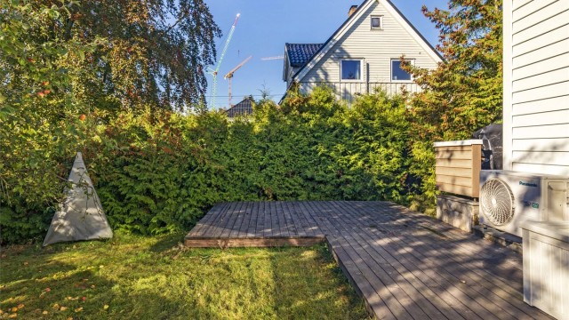Uteplassen er omkranset av hekk og trær som gir en usjenert ramme.