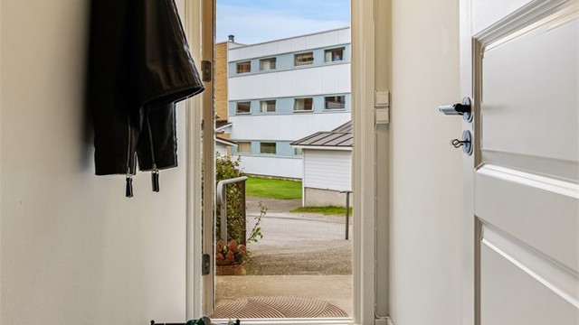 Egen inngangsdør i sandwichkonstruksjon med glassfelt gir adkomst direkte fra bakkeplan.