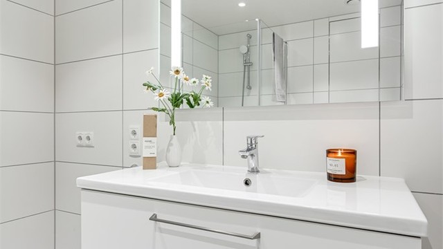 Badet er er innredet med servant i innredning og vegghengt toalett.