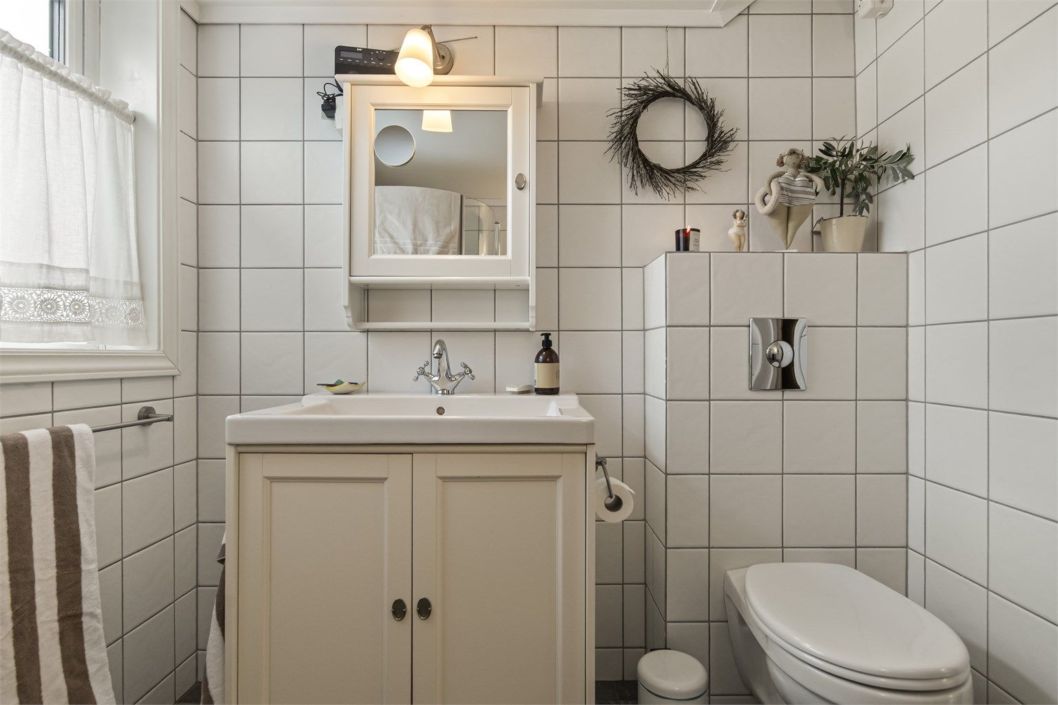 Badet er innredet med vegghengt toalett, servant i innredning og dusjhjørne