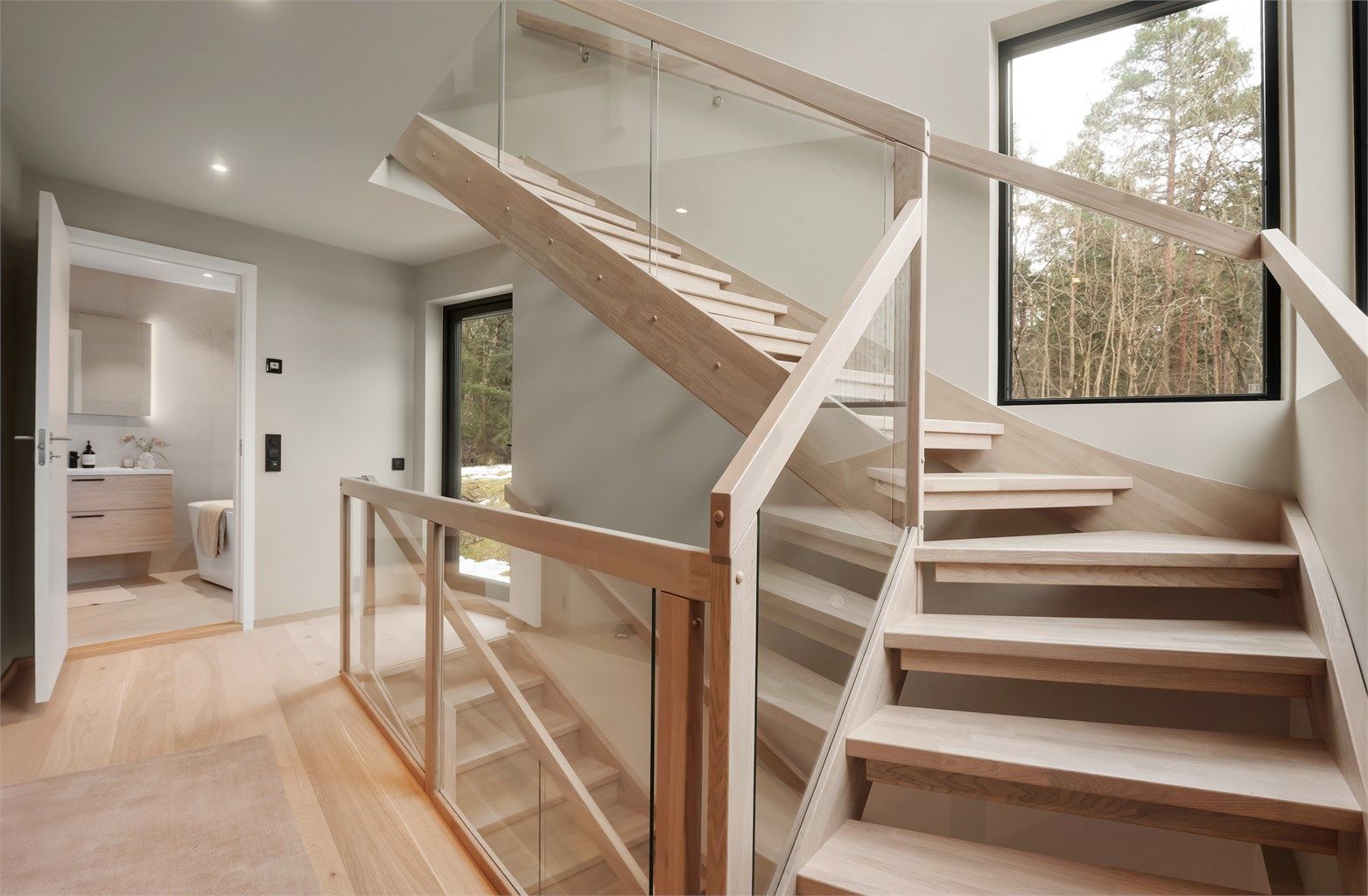 Trappen i hvitlasert eik med glassrekkverk er et sentralt designelement i boligen.