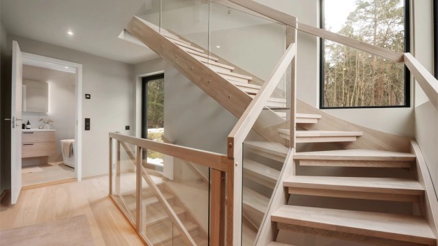 Trappen i hvitlasert eik med glassrekkverk er et sentralt designelement i boligen.