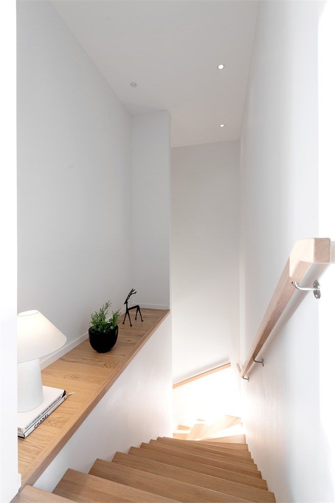 Innvendig trapp i tre mellom etasjene med tette vegger på begge sider. Det er montert håndrekke på vegg.