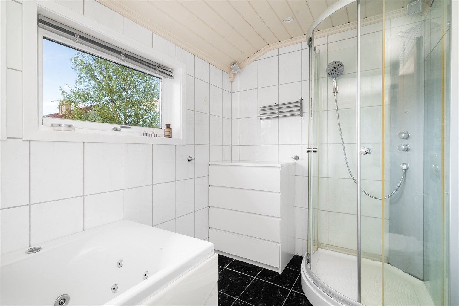 Badet er utstyrt med både badekar og dusjkabinett, og har flislagt gulv med elektriske varmekabler.