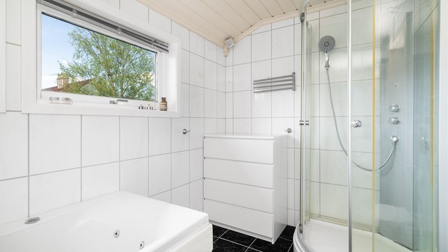 Badet er utstyrt med både badekar og dusjkabinett, og har flislagt gulv med elektriske varmekabler.