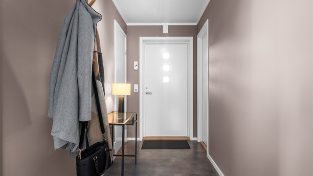 Lys entré med flislagte gulv med varme og slette vegger i lun farge