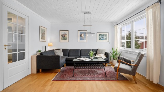 Stuen er et lyst og romslig samlingspunkt med parkett på gulvet og god plass til sofagruppe.