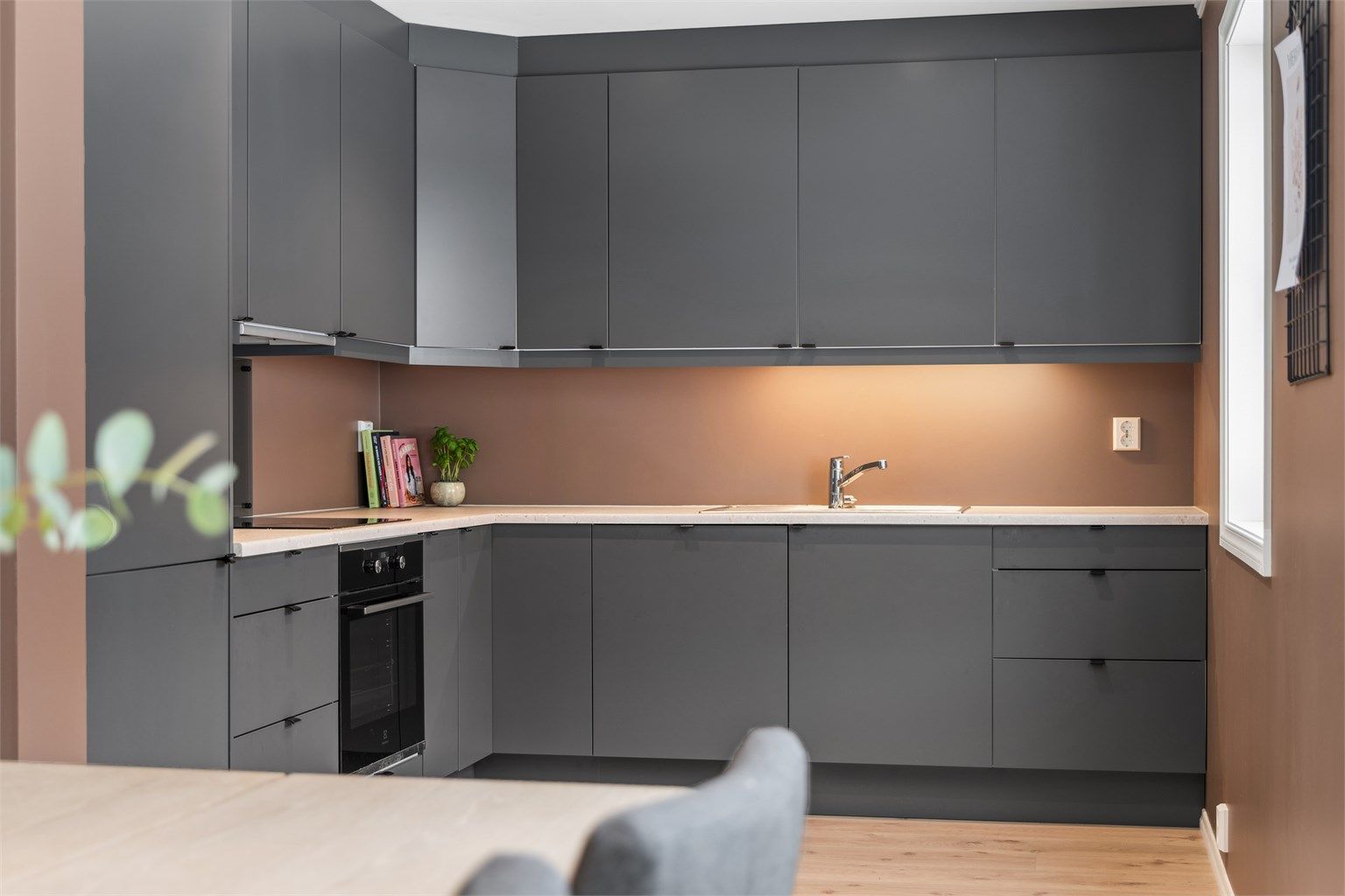 Kjøkkenet har moderne innredning fra byggeår med glatte fronter, laminert benkeplate og integrerte hvitevarer som stekeovn, platetopp, oppvaskmaskin og kjøleskap med fryser.