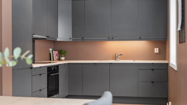 Kjøkkenet har moderne innredning fra byggeår med glatte fronter, laminert benkeplate og integrerte hvitevarer som stekeovn, platetopp, oppvaskmaskin og kjøleskap med fryser.