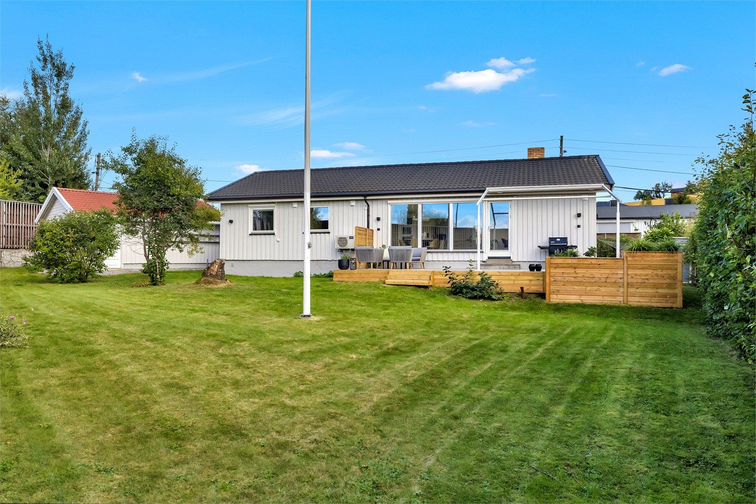 Eiendommen byr på en romslig, flat og pent opparbeidet tomt med god plen, frodige busker og hekker som gir en skjermet og privat atmosfære. Her er det rikelig med plass til både lek, hagearbeid og hyggelige sosiale sammenkomster. 