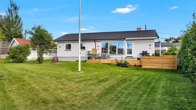 Eiendommen byr på en romslig, flat og pent opparbeidet tomt med god plen, frodige busker og hekker som gir en skjermet og privat atmosfære. Her er det rikelig med plass til både lek, hagearbeid og hyggelige sosiale sammenkomster.