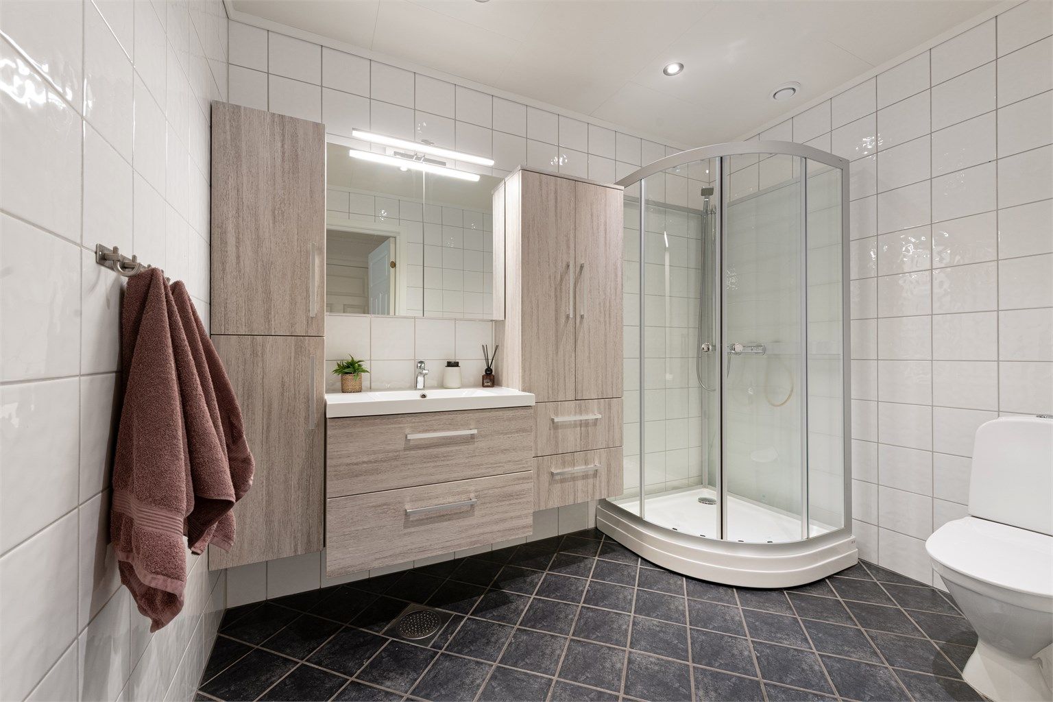 Badet i første etasje har flislagt gulv med gulvvarme, dusjkabinett og baderomsinnredning fra Lind, montert i 2017.