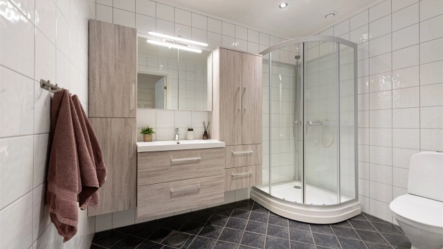 Badet i første etasje har flislagt gulv med gulvvarme, dusjkabinett og baderomsinnredning fra Lind, montert i 2017.
