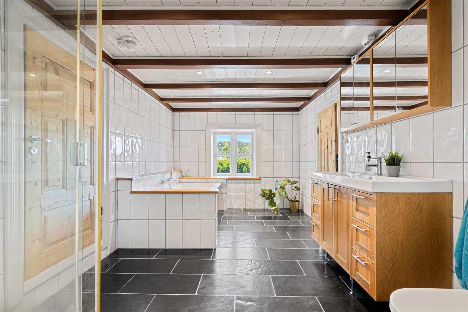 Badet i 2 etg. med varmekabler, badekar, wc, dusjkabinett, servant med skuffer og skap under og overskap. Inngang garderobe til venstre.