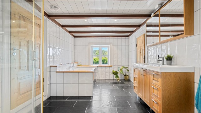 Badet i 2 etg. med varmekabler, badekar, wc, dusjkabinett, servant med skuffer og skap under og overskap. Inngang garderobe til venstre.