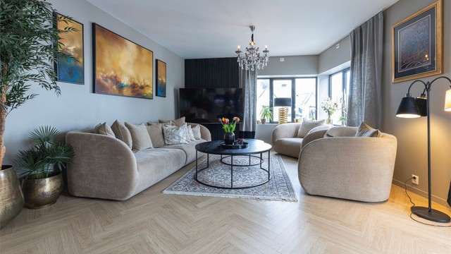 Elegant spilevegg tilfører stuen et moderne og stilrent uttrykk, mens lune og harmoniske fargetoner skaper en behagelig atmosfære. Fargevalgene gjør det enkelt å supplere med egne møbler og tekstiler.