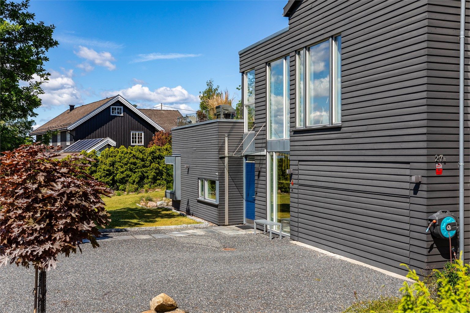Garasjeporten er en industriport kamuflert i samme kledning som ytterveggene. Huset har sensorstyrte utelamper designet av arkitekten.