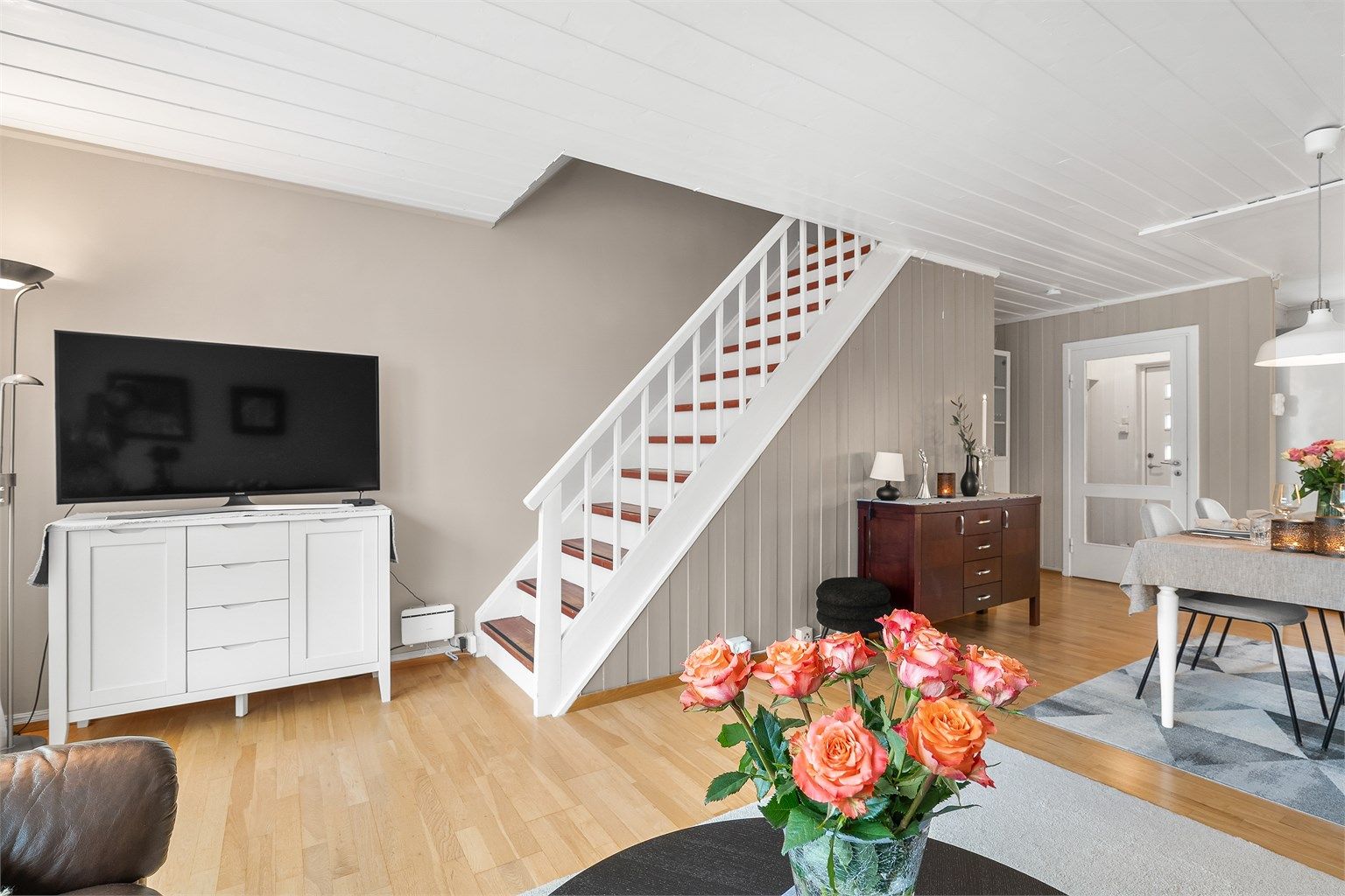 Stuen har laminatgulv, kombinasjon av veggpaneler, slette vegger og paneler i himling