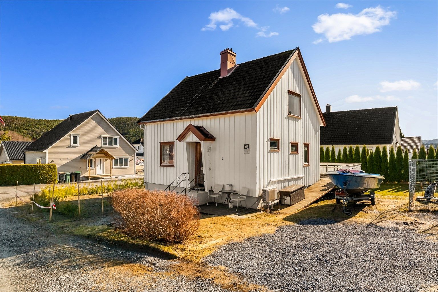 Tomten er opparbeidet med hekk mot nabo og veien. Gruset parkering i tillegg til garasje.