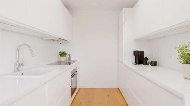 Det er rikelig med oppbevaringsplass i både skuffer og skap, og den gode benkeplassen gjør matlagingen enkel. Hvitevarene er sømløst integrert i innredningen.