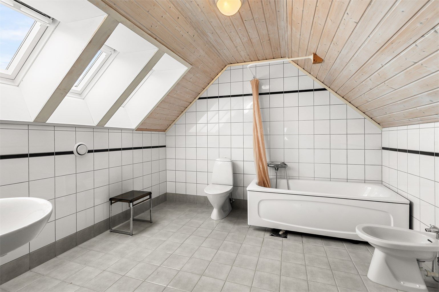 Romslig bad i loftsetasjen på 9,5 kvm med flislagte overflater, gulvvarme og takvinduer som slipper inn godt med naturlig lys.